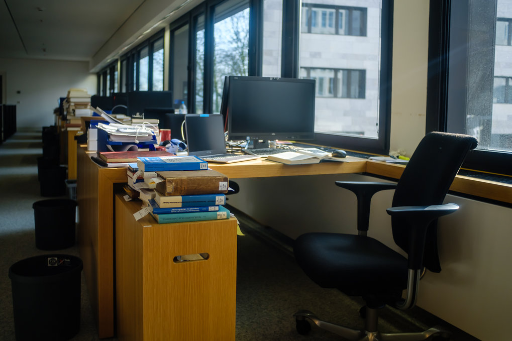 Desk with computers and many books in a library reading room